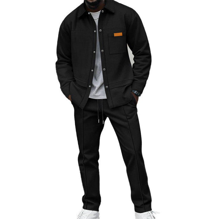 Model wearing the set in black, shirt buttoned over a grey tee, hands in pockets 1