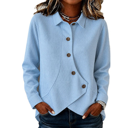Model wearing the waffle-knit jumper in pale blue, hands in jeans pockets, showing the collar, brown buttons and curved asymmetrical hem. 3