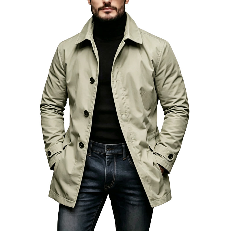 Man wearing the coat in pale sage green, hands in pockets, over a black polo neck and jeans 4