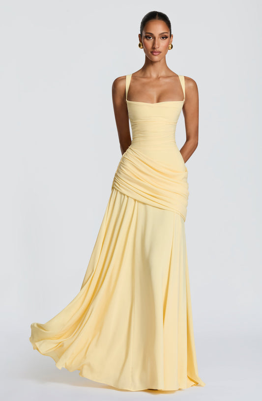 Front view of the pale yellow chiffon maxi dress on a model, showing the square neckline, draped hip detail and flowing skirt. 1