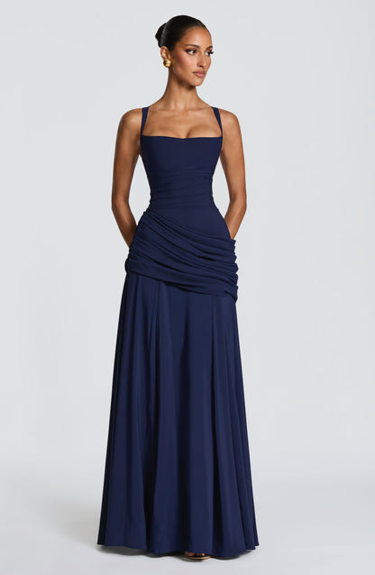 Navy dress full length, front view, with hands in the side pockets and a floor-skimming skirt 8