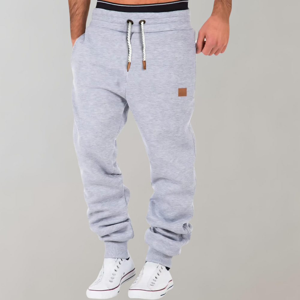 Model wearing light grey joggers with white drawstring and ribbed ankle cuffs, with white trainers 4