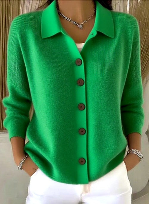 Model wearing the vivid green version of the collared knit cardigan with brown buttons, paired with white trousers. 5