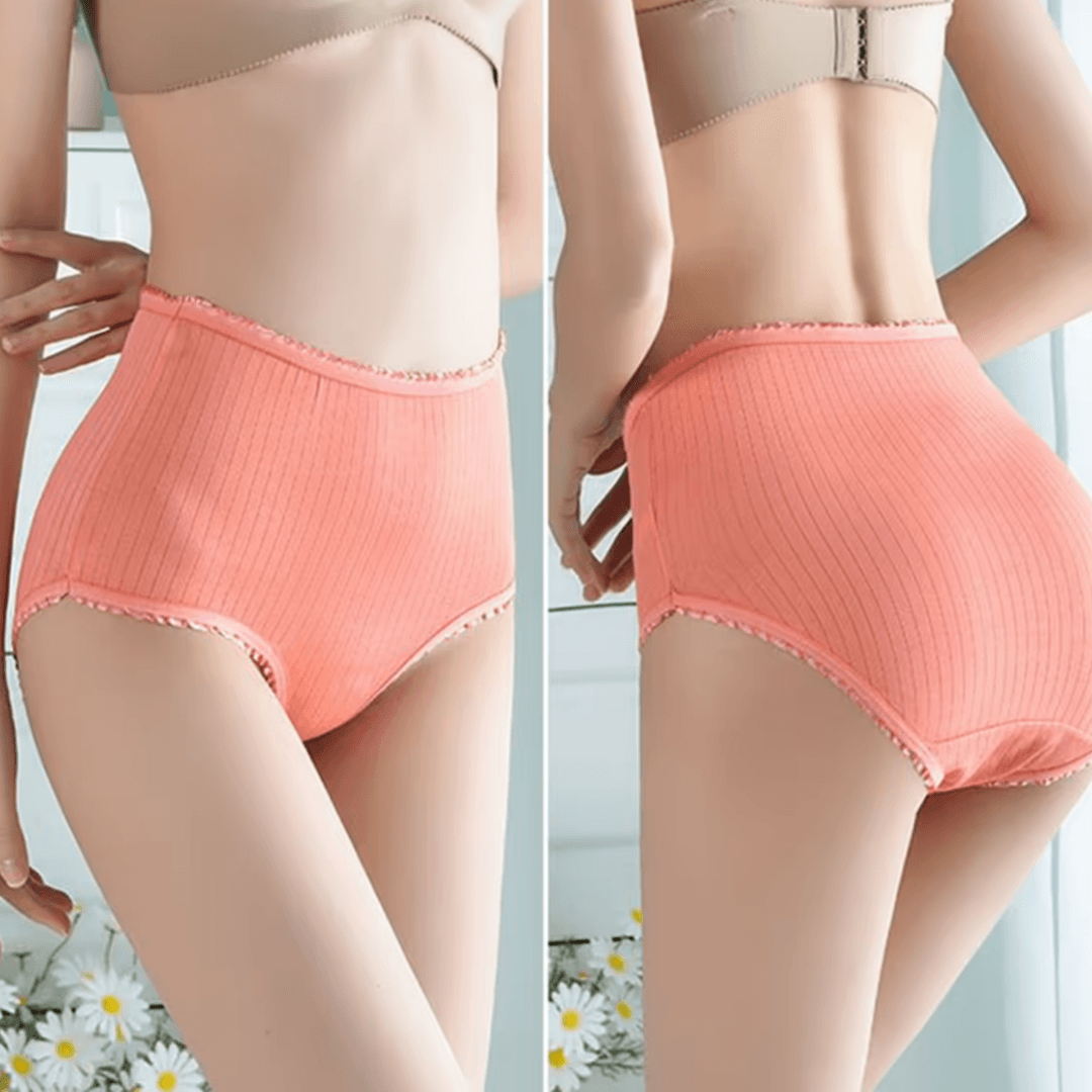 Side-by-side front and back views of a model wearing coral ribbed high-waisted briefs with frilled edges, daisies in the foreground. 3