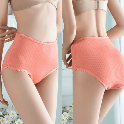 Side-by-side front and back views of a model wearing coral ribbed high-waisted briefs with frilled edges, daisies in the foreground. 3