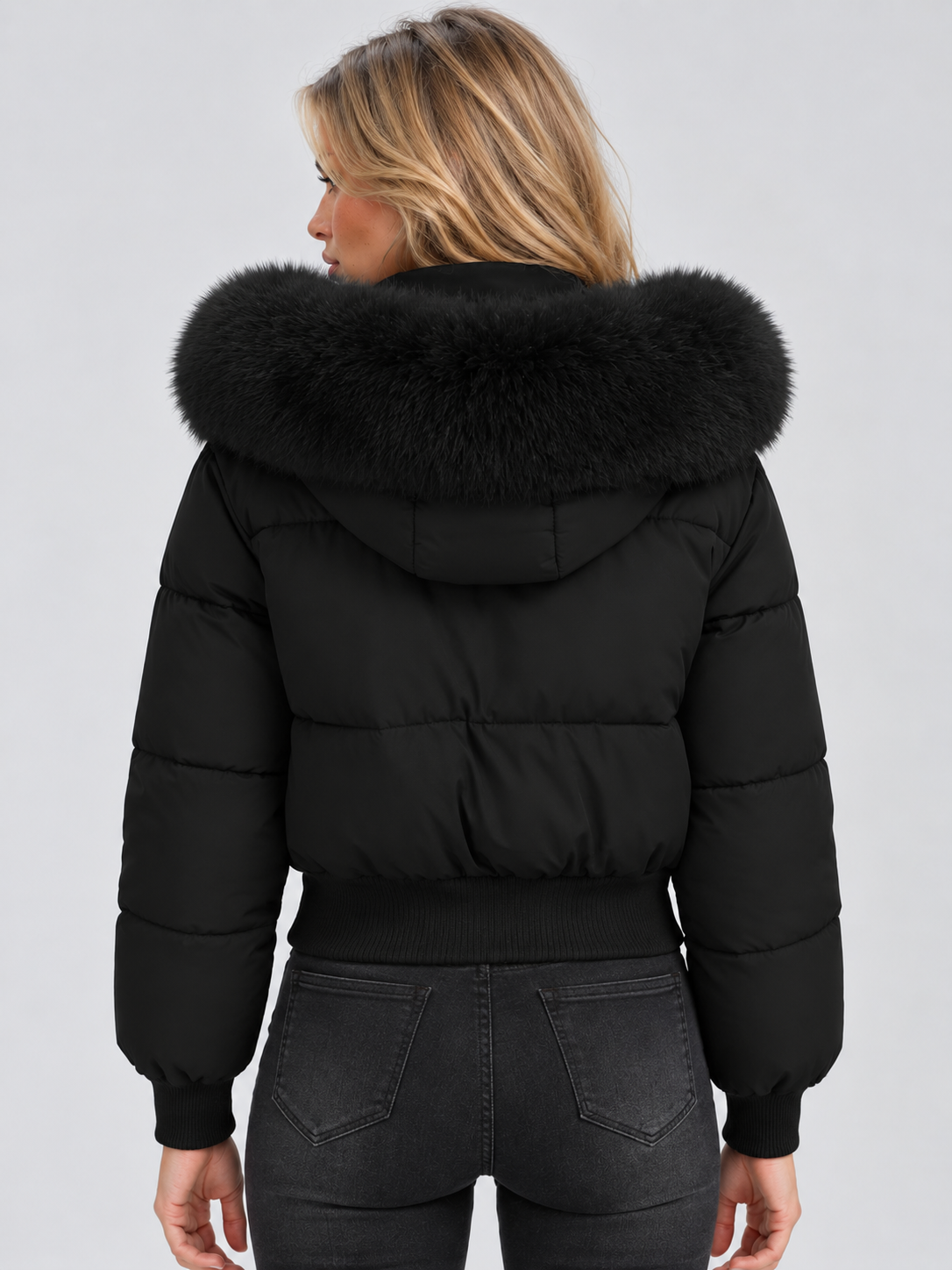 Back view of the black cropped jacket on a model, showing the large fluffy hood trim 2