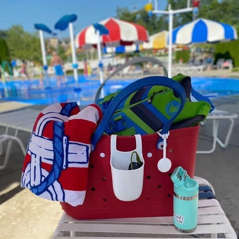 Red tote on a poolside lounger packed with a striped towel and green life jacket, with a white pocket and teal bottle beside it. 24