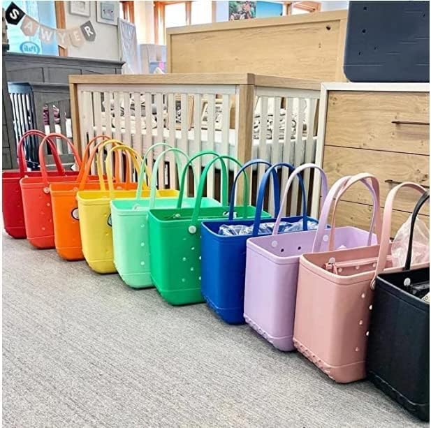 Row of totes in rainbow colours, from red through yellow, green and blue to pink and black, lined up on a carpet. 25
