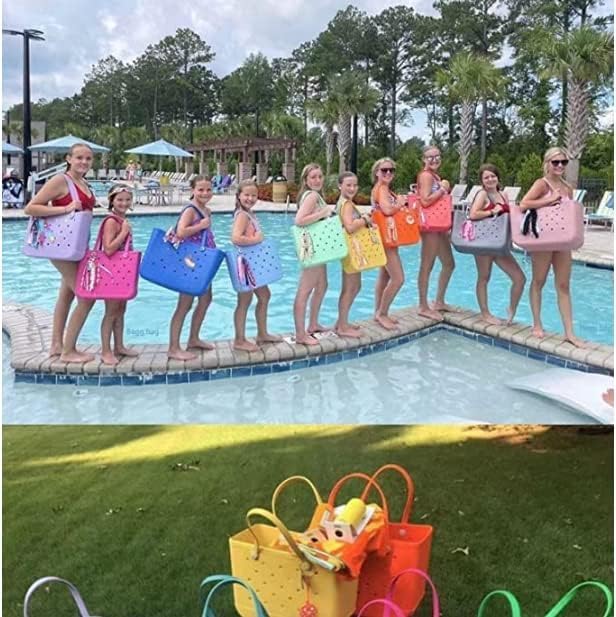 Girls and women posing in a line on a pool edge, each holding a different brightly coloured tote, with more totes on grass below. 26