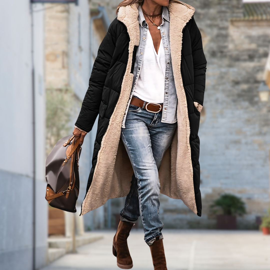Model walking down a street in a black quilted long coat lined with cream fleece 4
