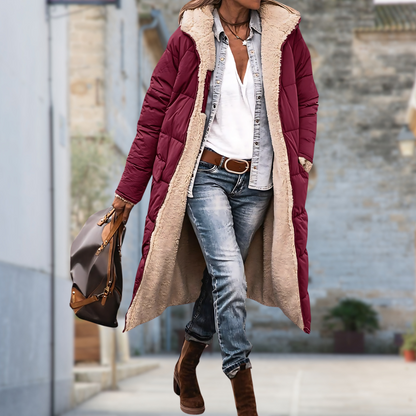 Model walking down a street in a burgundy quilted long coat with cream fleece lining 6