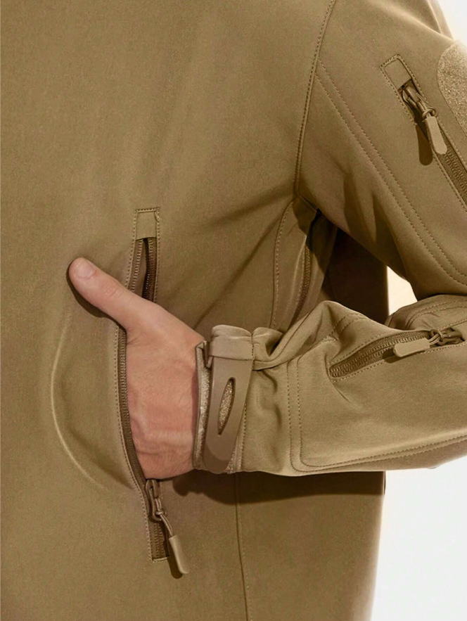 Close-up of a tan jacket on a model, with a hand in the zipped hand pocket and the adjustable cuff strap visible. 13