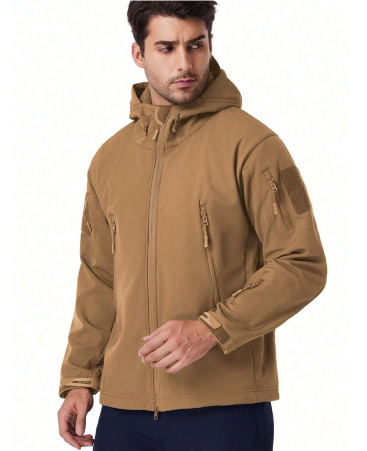 Model in the tan hooded jacket, turned slightly sideways, showing the full-length front zip, chest pockets and hook-and-loop sleeve patch. 16