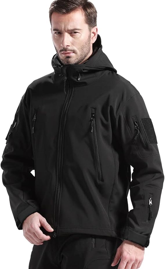 Man wearing the black hooded jacket zipped up, facing the camera, showing chest and sleeve zip pockets and a hook-and-loop patch. 2